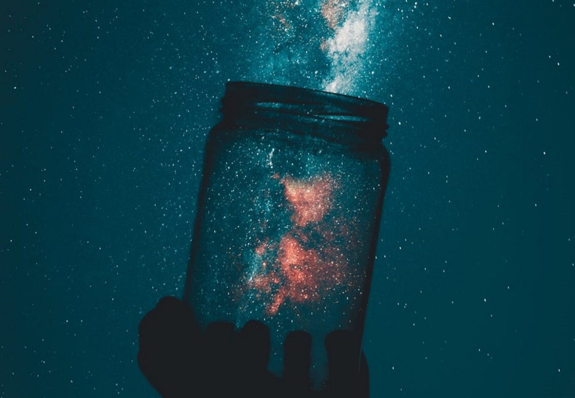 A photograph of a glass mason jar held up to starlight.