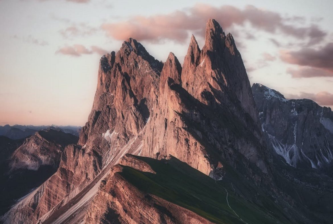 A photograph of a mountain under a pink-beige sky.