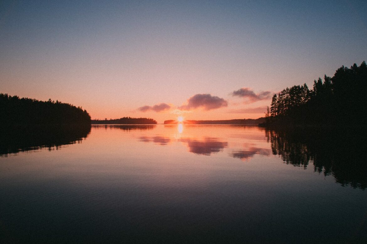 Photograph of the sun setting over a Finnish lake. Photo taken by Markus Watkins.