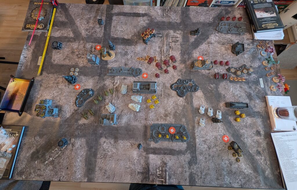 An overhead photo of the entire game table, with both armies deployed. The loyalist Imperial Fists and Solar Auxilia face off against the Word Bearers, Dark Mechanicus, and traitor Auxilia. 